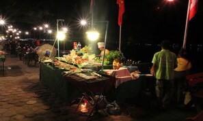 A nighttime outdoor food market with various food stalls and a person in the background. - Suksavanh River Hotel (Vientiane)