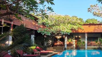 A pool area with lounge chairs, a swimming pool, and surrounding greenery.