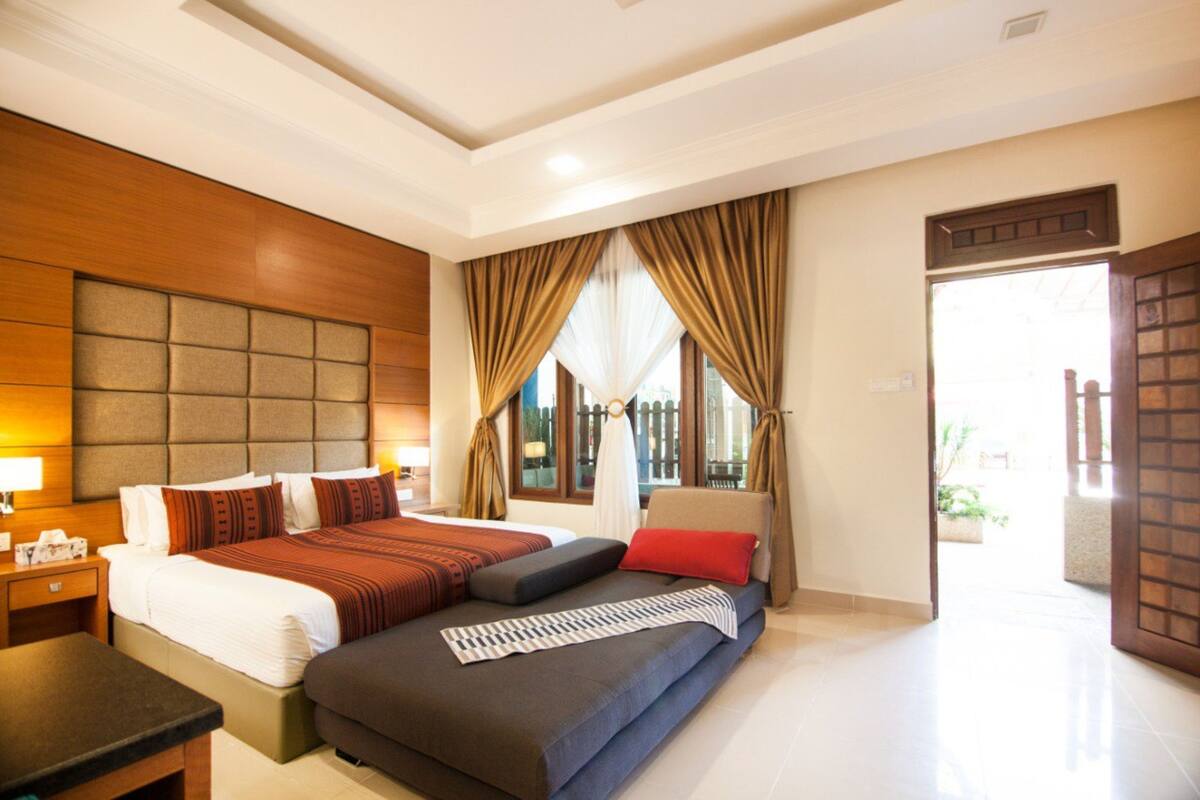 A hotel room with a large bed, a sofa, and a desk.