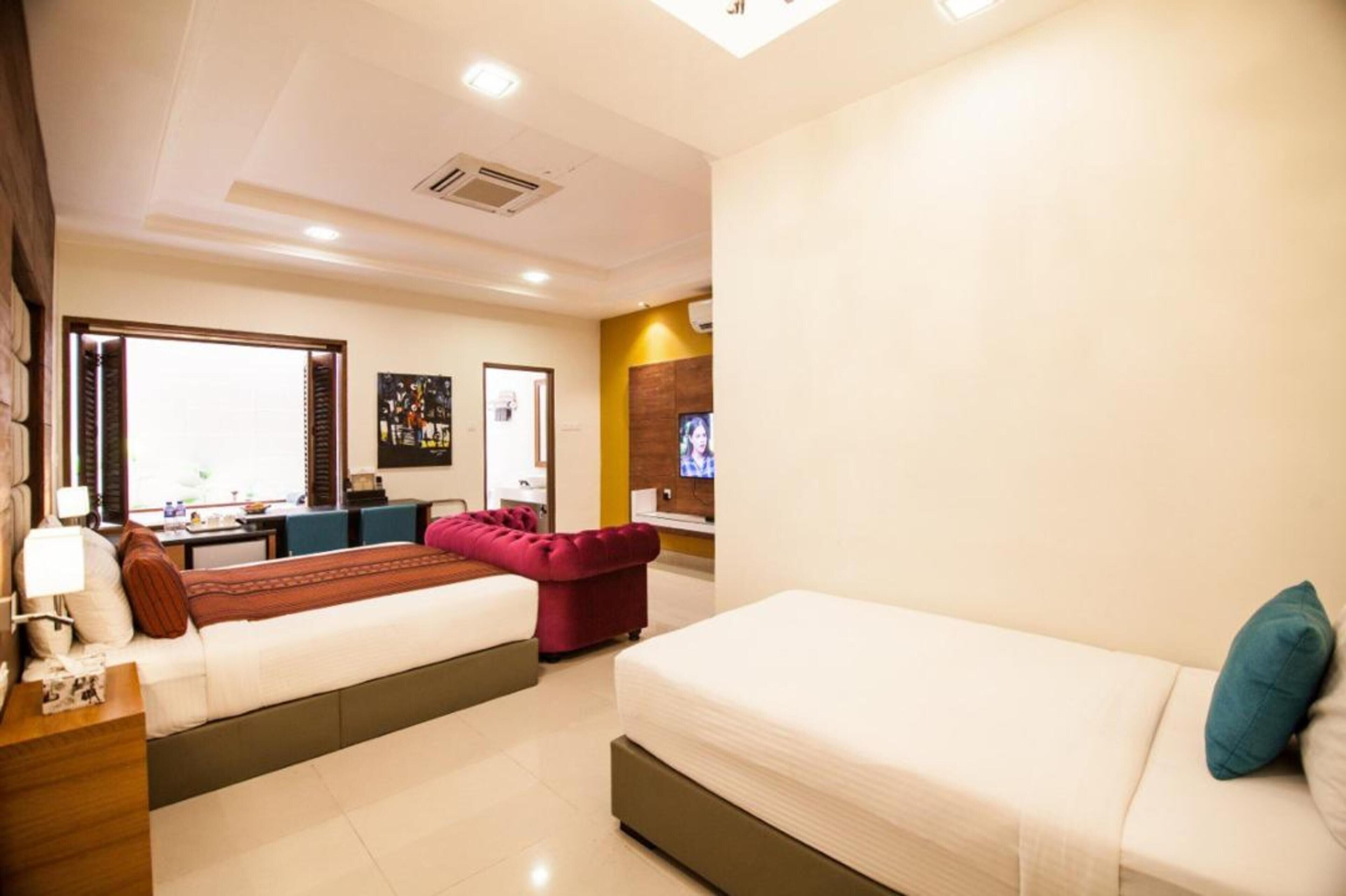 A hotel room with two beds, a desk, and a TV.