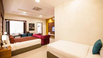 A hotel room with two beds, a desk, and a TV.
