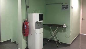 A room with a water dispenser, a fire extinguisher, a ironing board, and a sign on the wall. - Best Seven Motel (Langkawi)