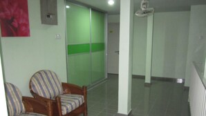 A room with a green sliding door, a wooden chair with striped upholstery, and a white radiator. - Best Seven Motel (Langkawi)