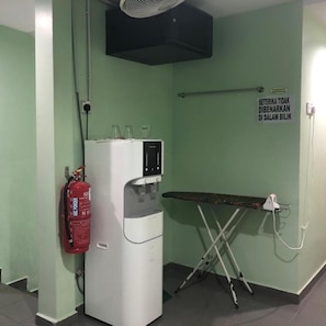 A room with a water dispenser, a fire extinguisher, an ironing board, and a sign on the wall. - Best Seven Motel (Langkawi)