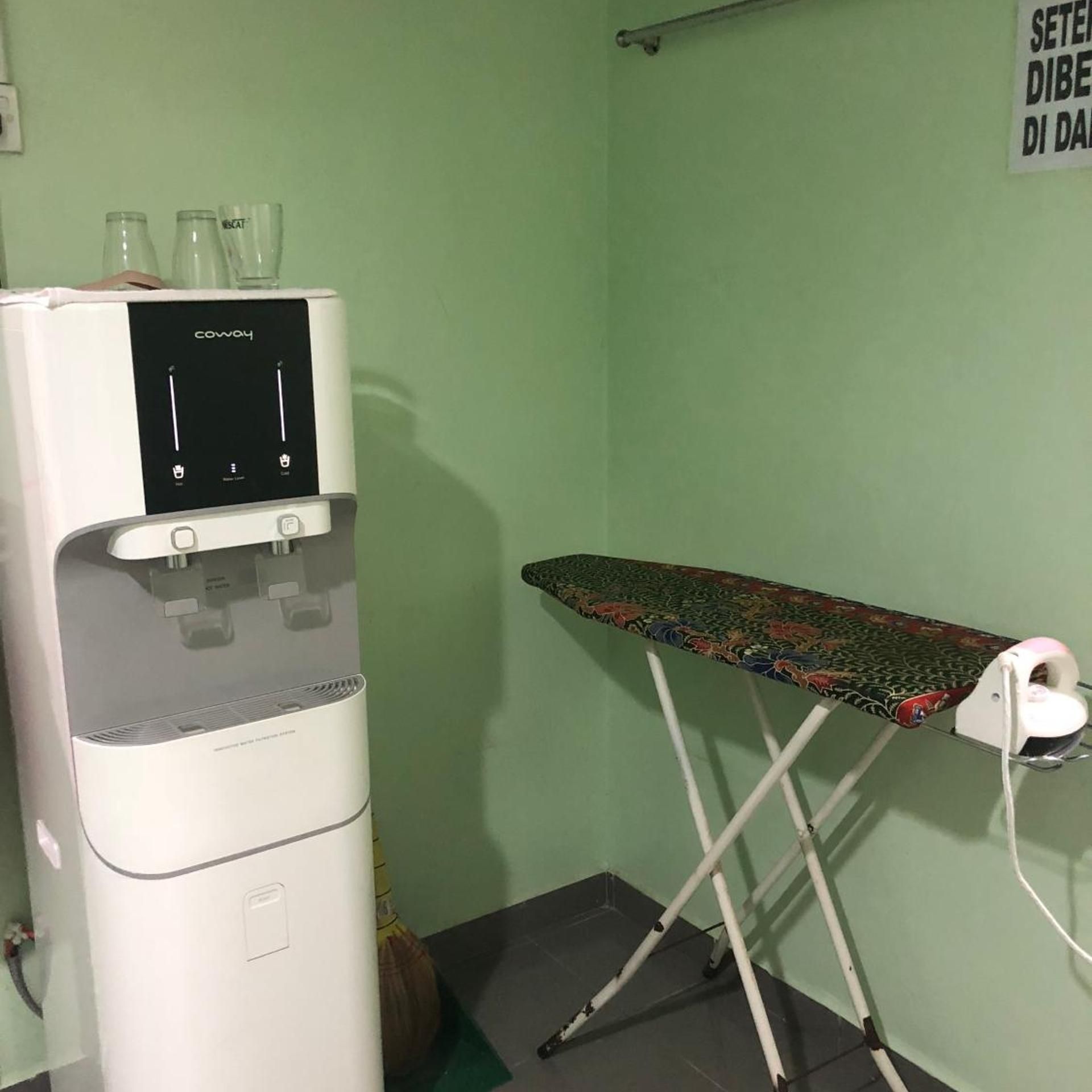 A room with a water dispenser and an ironing board.
