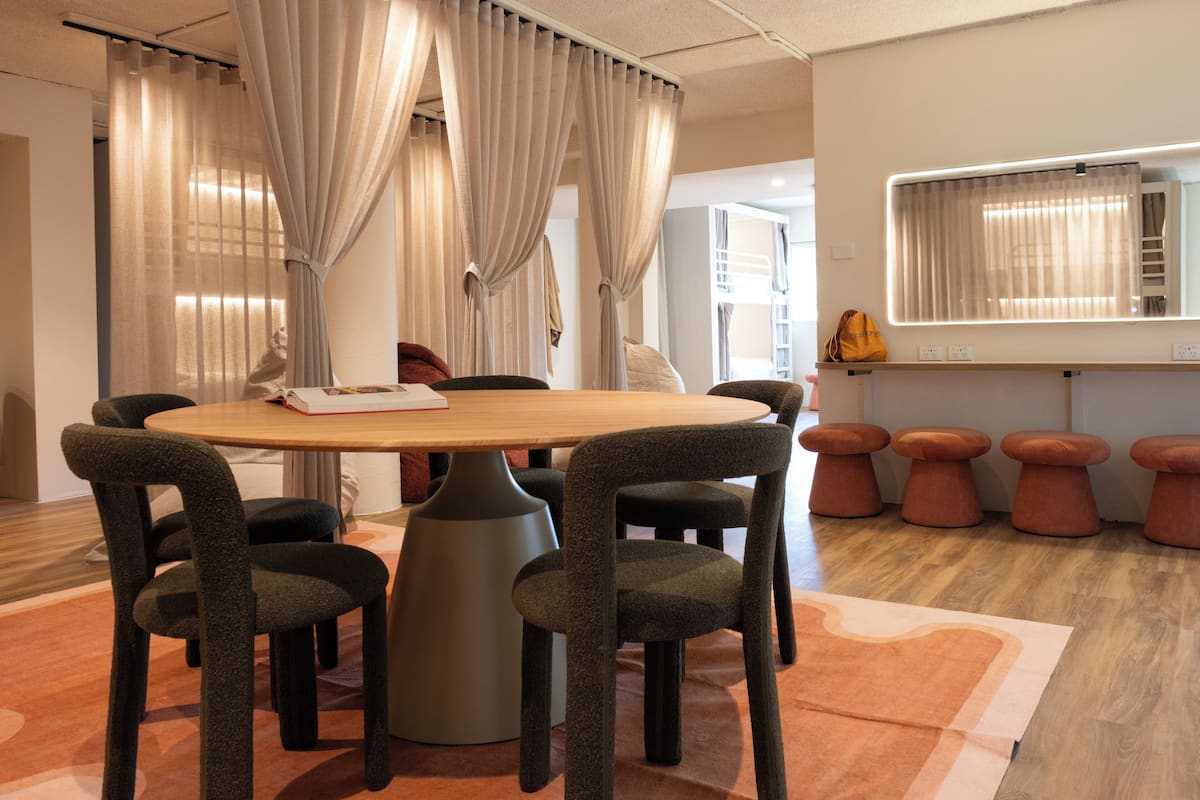Un salón de conferencias con una mesa redonda, seis sillas, un espejo grande y una ventana con cortinas.