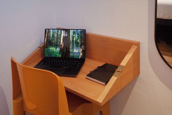 Ein Laptop auf einem Holztisch, daneben ein Notizbuch.