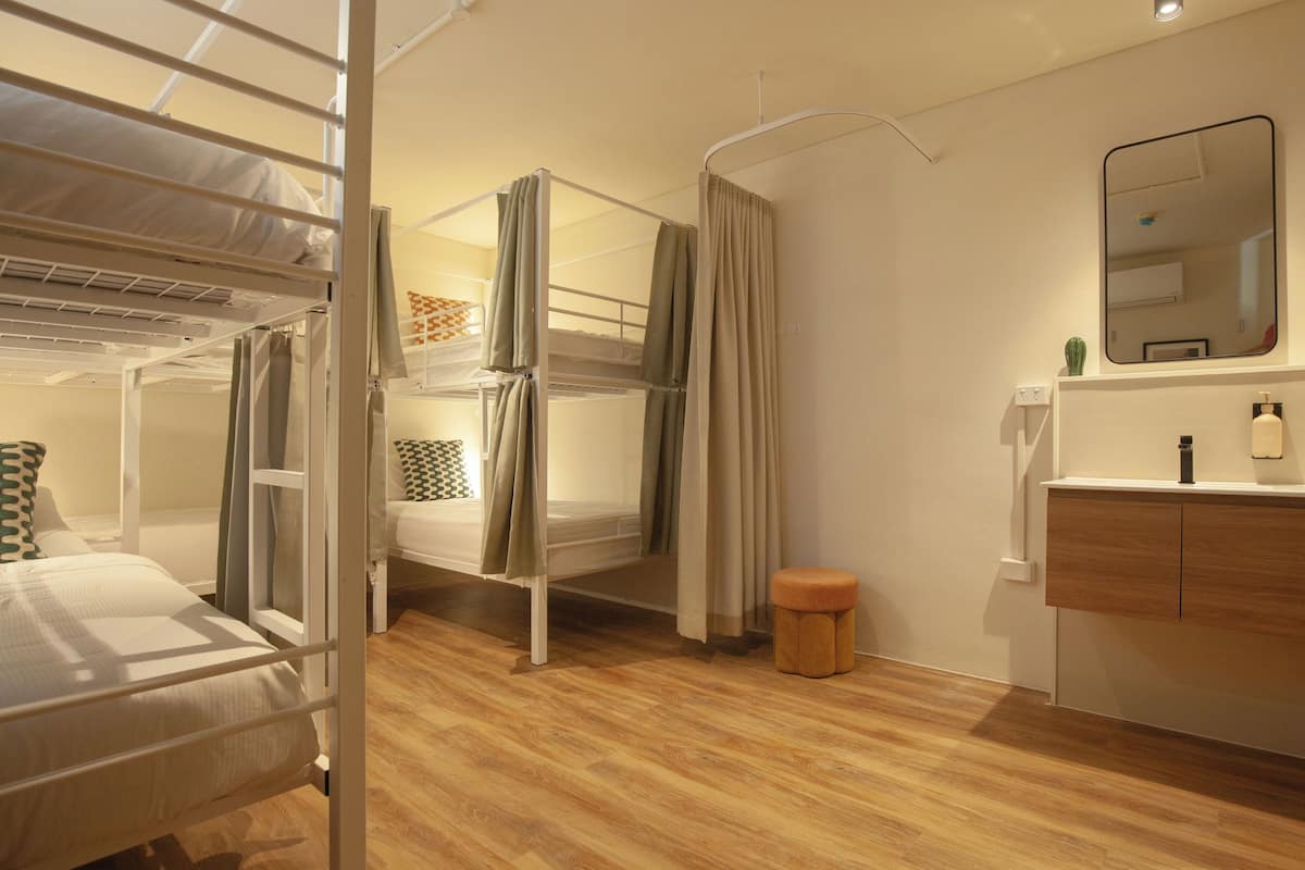 Una habitación con literas, un taburete pequeño, un espejo y un armario de madera.