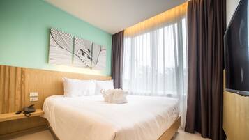 Quarto de hotel com uma cama grande, mesa de cabeceira com telefone e janela com cortinas.