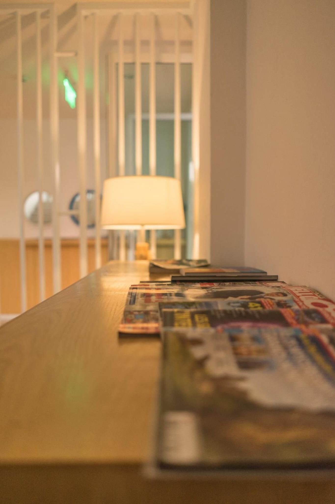 Una mesa de madera con revistas y una lámpara.