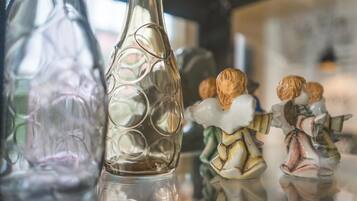 A clear glass bottle with a reflective surface, a decorative figurine, and a blurred background.