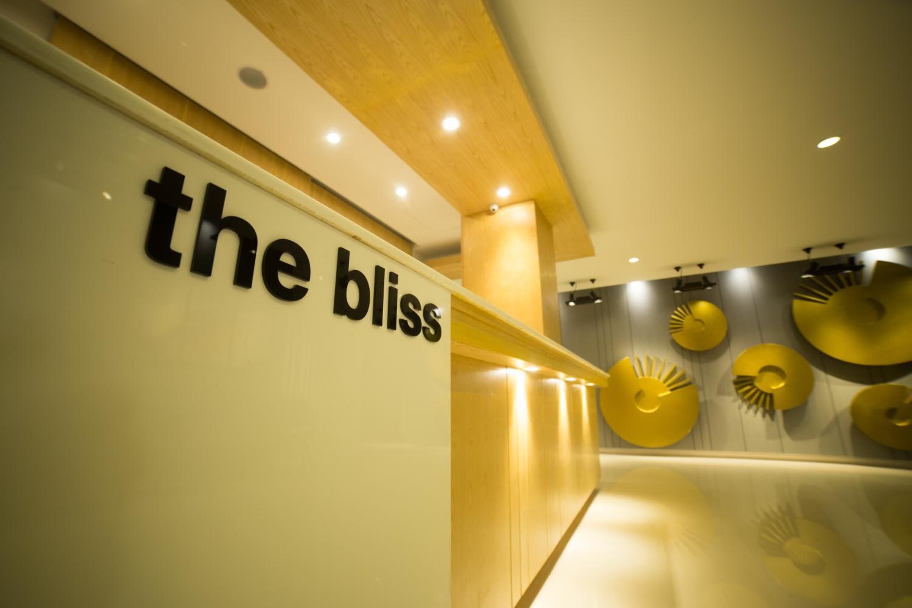 A sign with the text "the bliss" in a modern interior with a wooden ceiling and decorative wall elements.