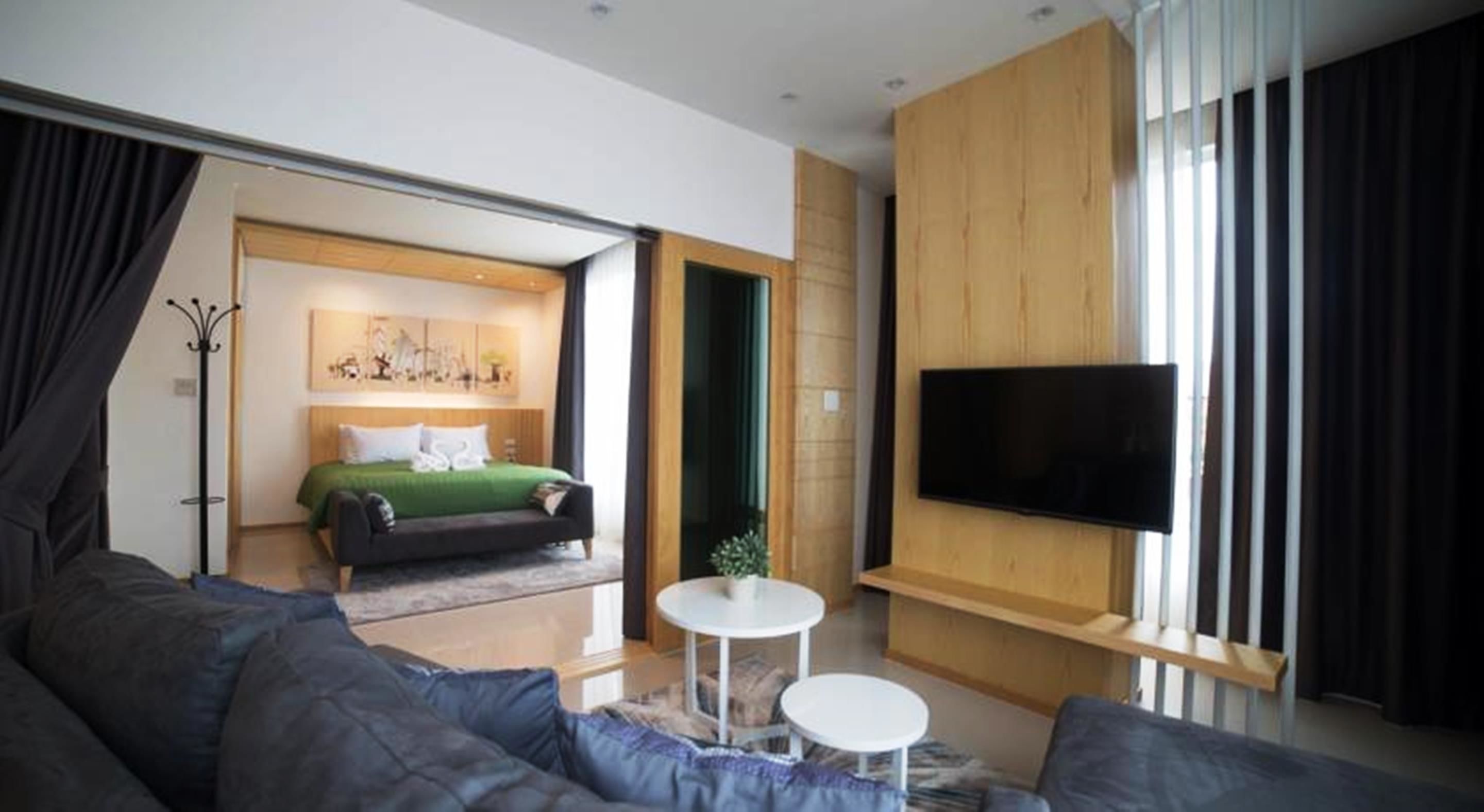 Una camera d'albergo moderna con un letto grande, una TV a schermo piatto, un divano e un tavolino.