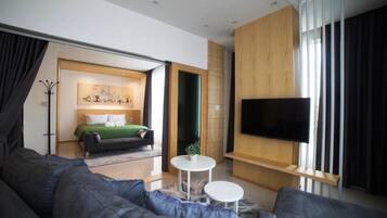 Una camera d'albergo moderna con un letto grande, una TV a schermo piatto, un divano e un tavolino.