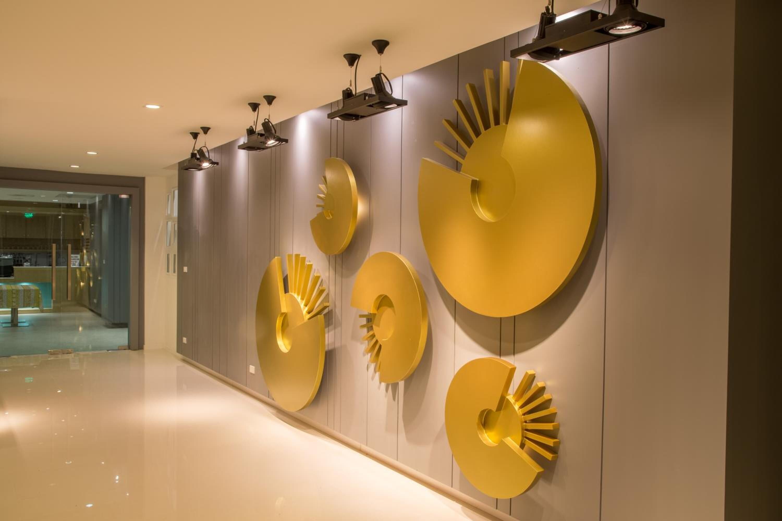 A modern hallway with a polished floor and a series of golden wall art pieces.