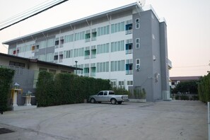 A multi-story building with a parking area and a silver pickup truck parked in front.