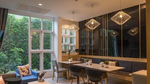 Une cuisine moderne avec un coin repas, de grandes fenêtres et des luminaires suspendus.