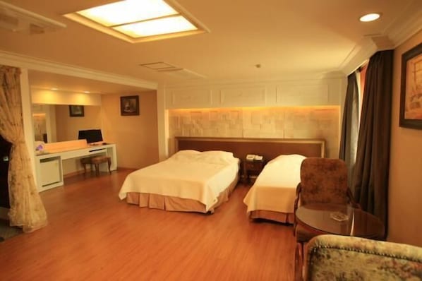 A hotel room with two beds, a desk, and a chair.