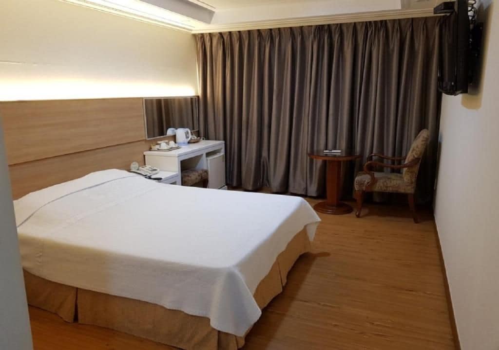 Une chambre d’hôtel avec un lit, un bureau, une chaise et une petite table.