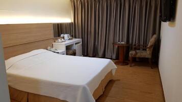 Une chambre d’hôtel avec un lit, un bureau, une chaise et une petite table.