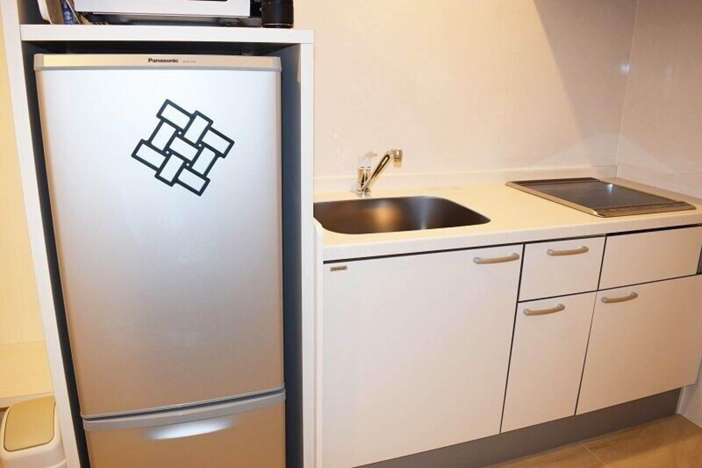 Una cucina compatta con frigorifero, lavello e mobili bianchi.
