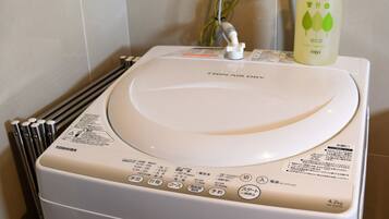 A white washing machine with a front control panel, a bottle of eco-friendly cleaner, and a metal rack.