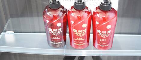 Three red bottles of hair care products on a clear shelf.