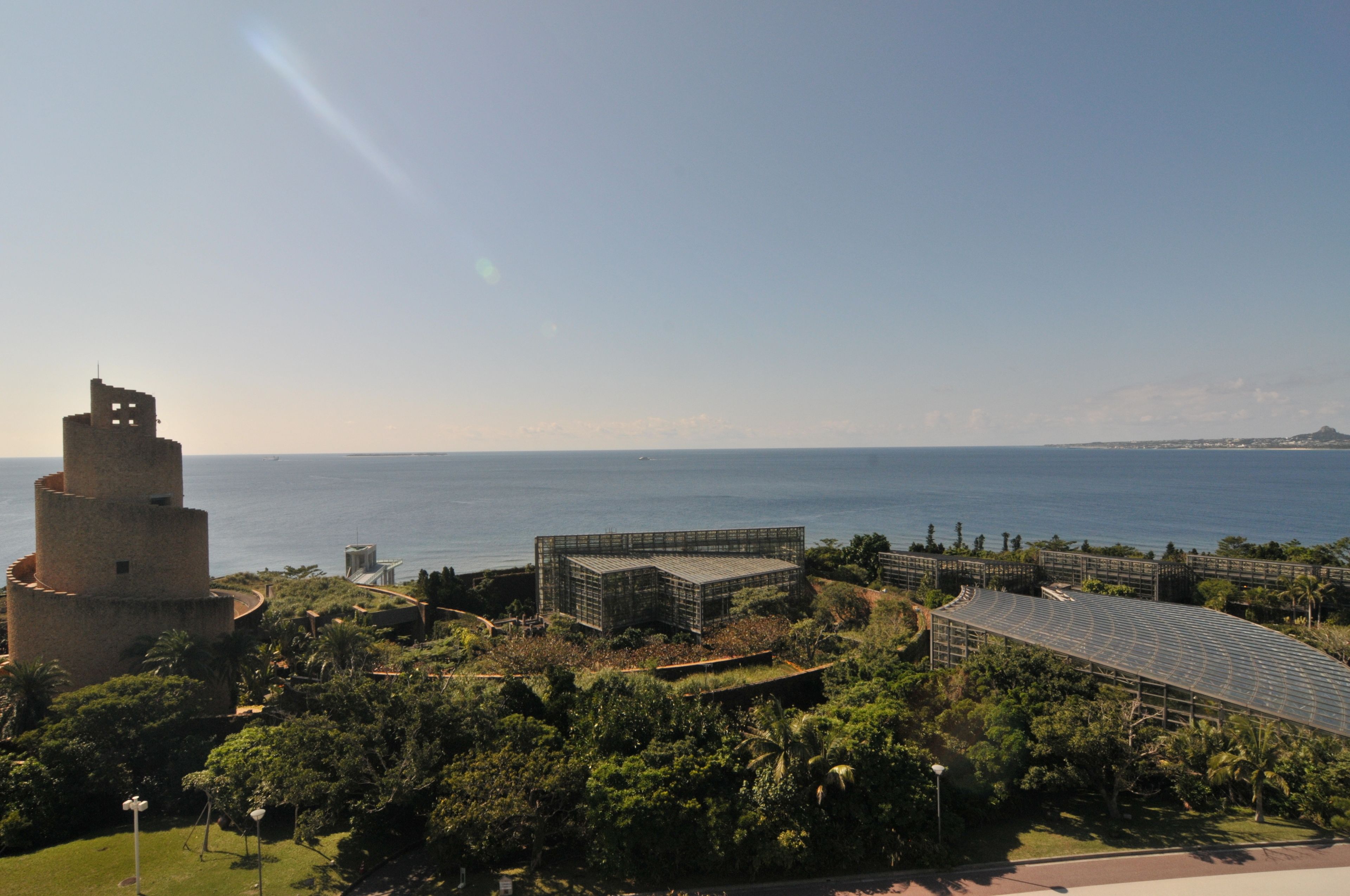 A coastal view with a historic tower and modern buildings, surrounded by lush greenery.