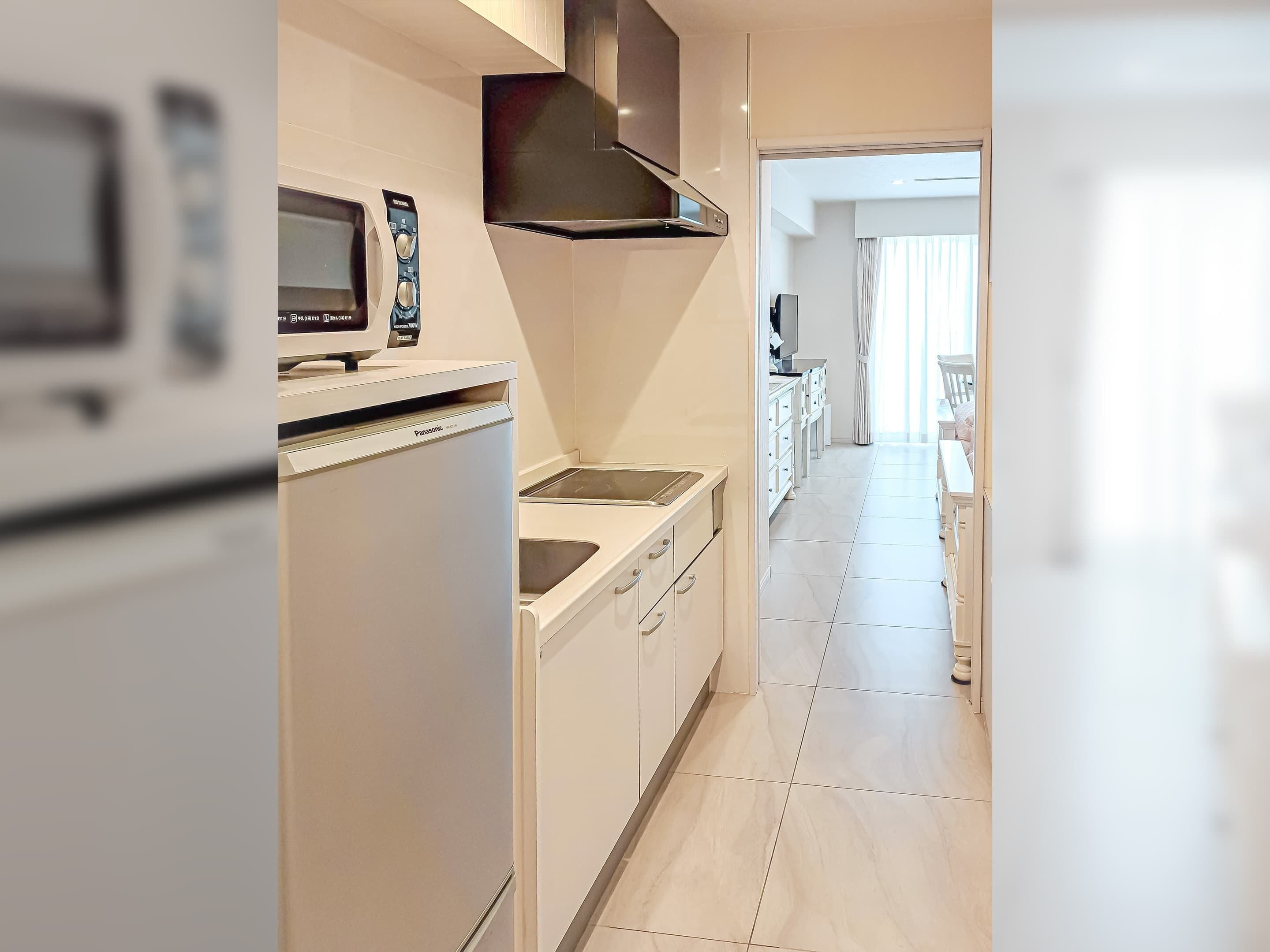 Una cocina moderna con armarios blancos, microondas integrado y campana extractora de acero inoxidable.