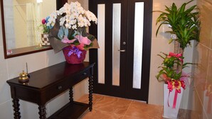 Una consola de madera con un jarrón de flores y una pequeña figurita.