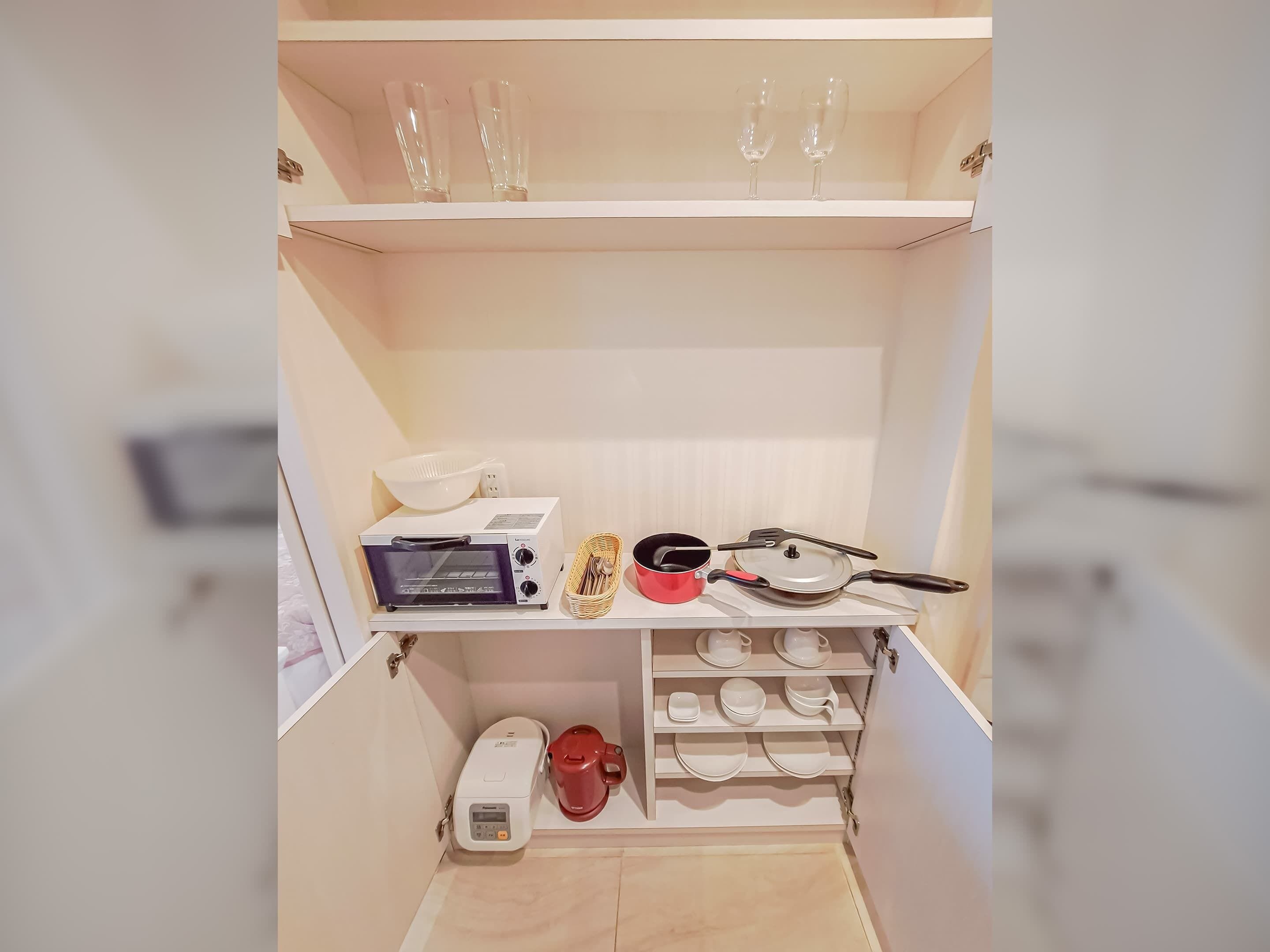 A compact kitchen with a toaster oven, a red coffee maker, and a small sink.