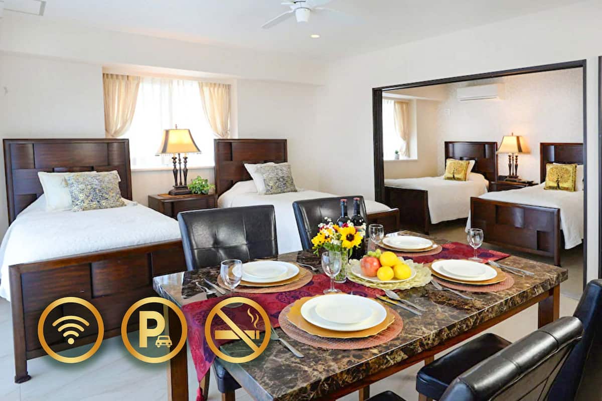 A hotel room with a large bed, a smaller bed, a dining table set for two, and a mirror reflecting the room.