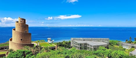 A historic tower and modern building with a view of the ocean.
