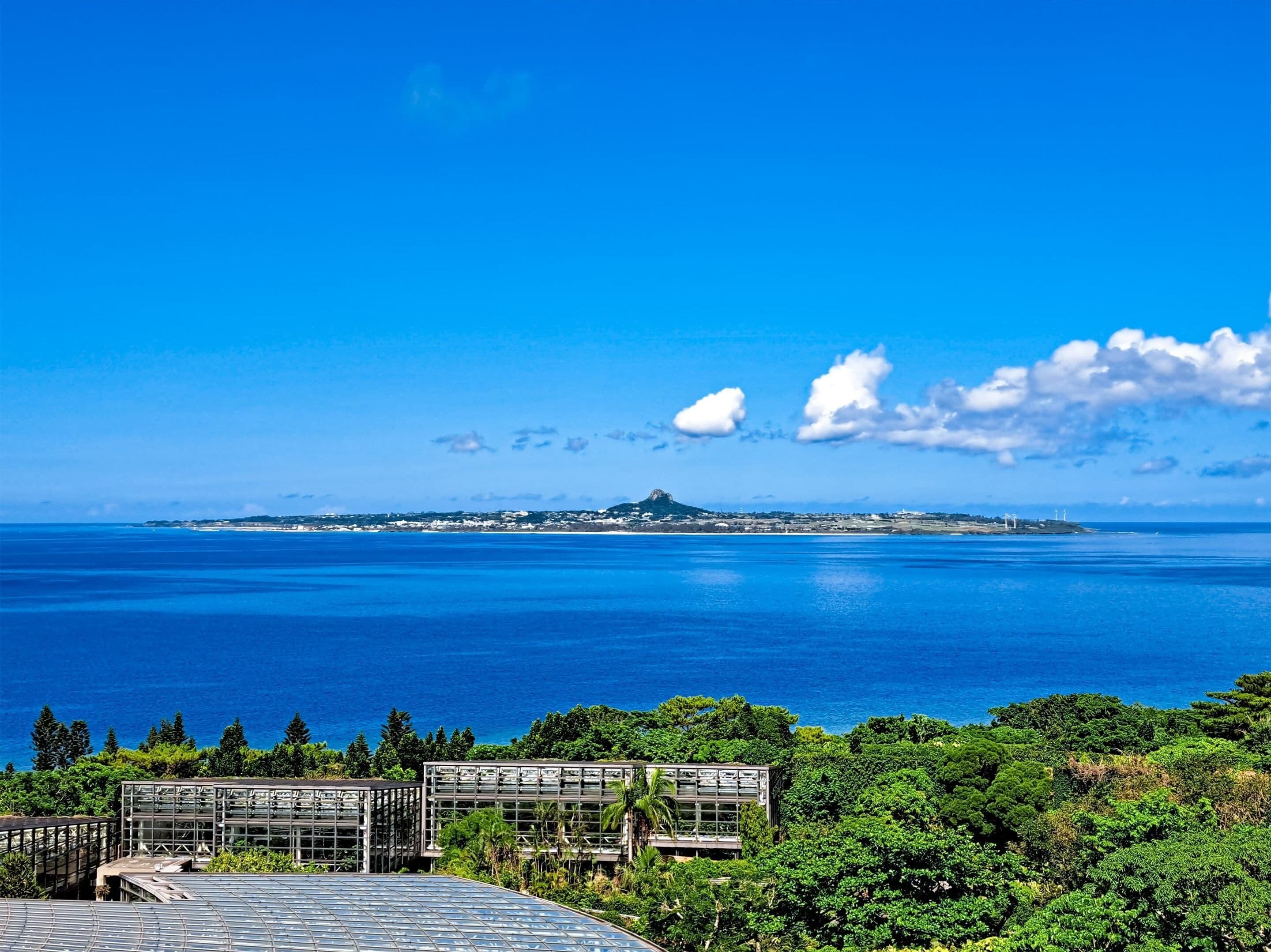 A coastal view with a clear sky, a distant island, and a greenhouse structure.