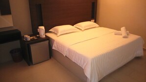 Ein Hotelzimmer mit einem Bett, einem Nachttisch, einer Lampe und einem Papierkorb.