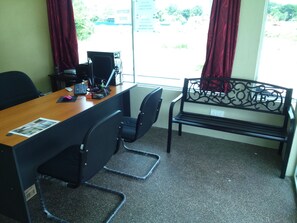 A conference room with a wooden table, black chairs, a black metal bench, and a window with red curtains. - Ziella De Villa (Langkawi)