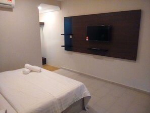 Habitación de hotel con cama, televisión de pantalla plana montada en la pared y una mesita de noche.