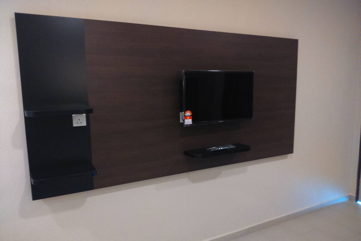 A wall-mounted entertainment unit with a flat-screen TV, a small shelf, and a power outlet.