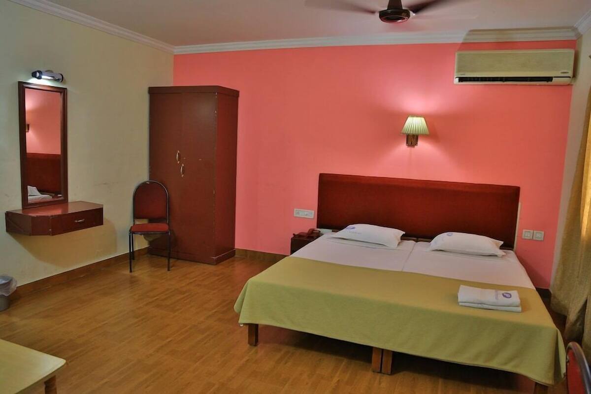 A hotel room with a bed, a wardrobe, a desk, and a mirror.
