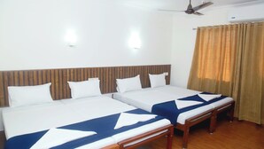A hotel room with two beds, wooden headboard, white walls, ceiling fan, air conditioning unit, and a window with curtains. - Hotel Srinivas (Kanayannur)