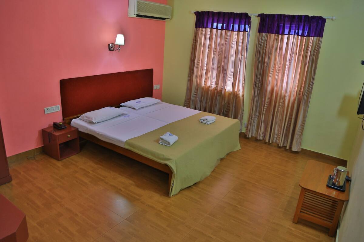A hotel room with a bed, a nightstand, a lamp, and curtains.