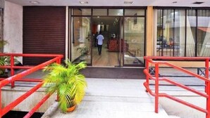 A hotel entrance with a glass door, a red staircase, and a potted plant. - Hotel Srinivas (Kanayannur)