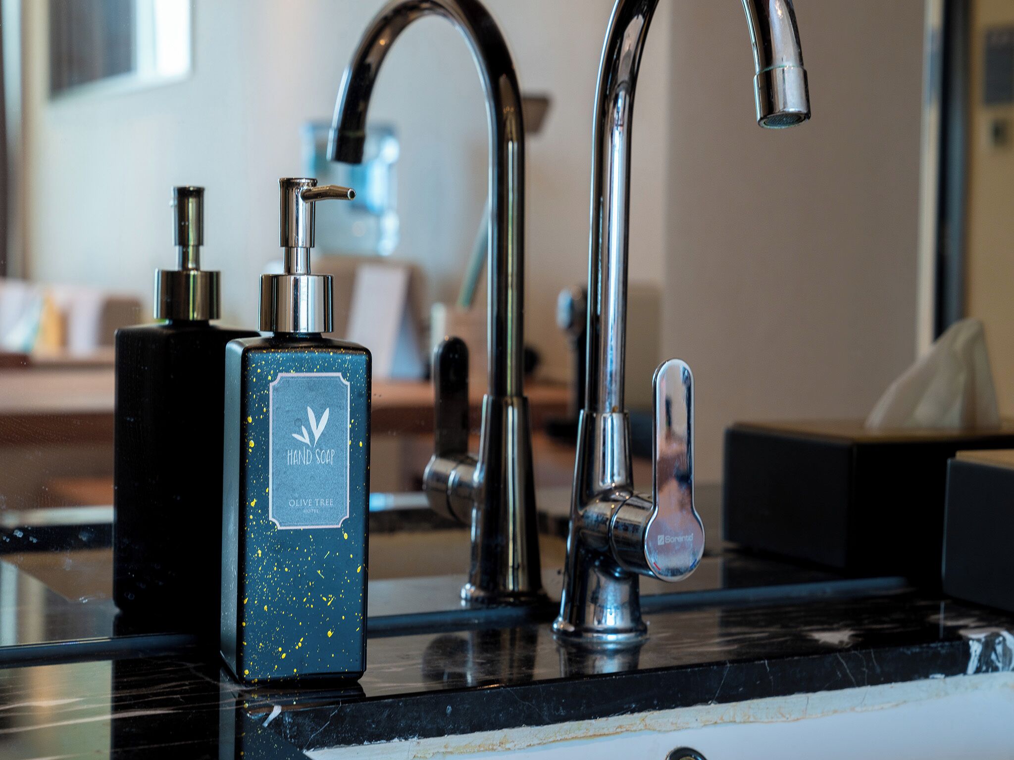 Une salle de bain dotée d’un lavabo moderne, d’un distributeur de savon liquide et d’un robinet.