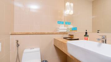 A modern bathroom with a toilet, bidet, and sink. There are towels and toiletries on the counter.