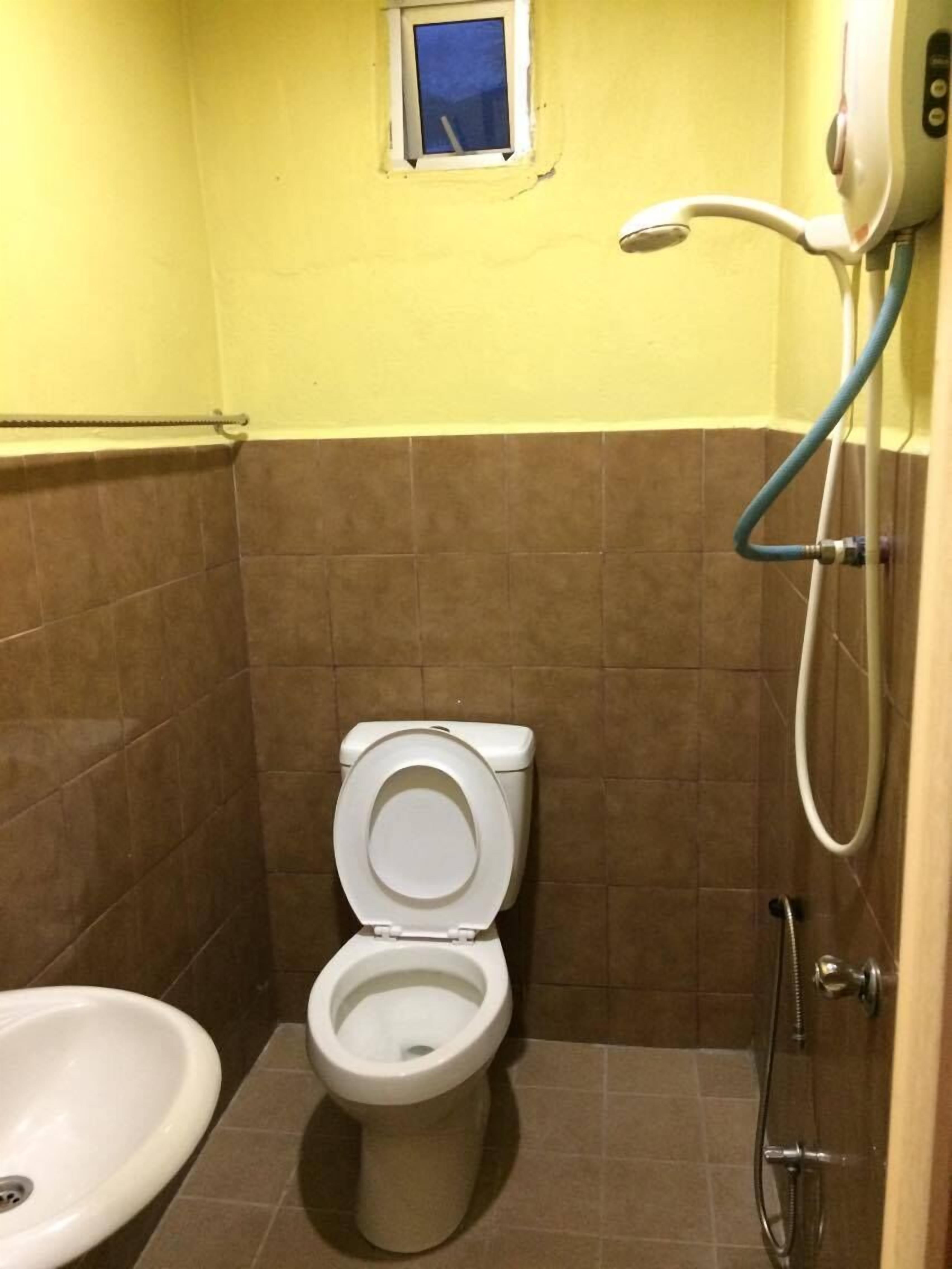 A bathroom with a toilet, a small window, and a shower.