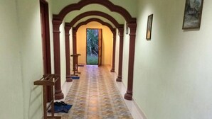 A hallway with patterned tile flooring, wooden columns, and a welcome mat. - Bohok Guest House (Langkawi)