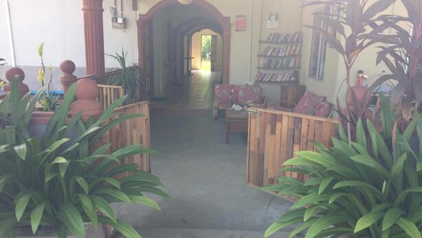 A staircase leading to a hallway with a wooden railing, potted plants, and a bookshelf with books. - Bohok Guest House (Langkawi)