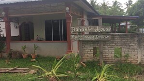 A guest house named "Bohok Guest House" with a signboard, a covered porch, and a stone wall. - Bohok Guest House (Langkawi)