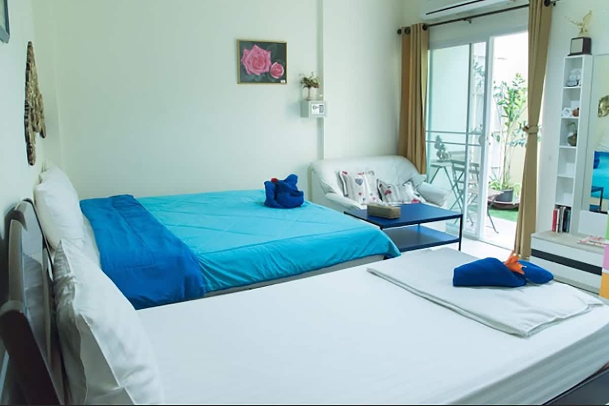 Een slaapkamer met een bed, een stoel, een tafeltje en een boekenkast.