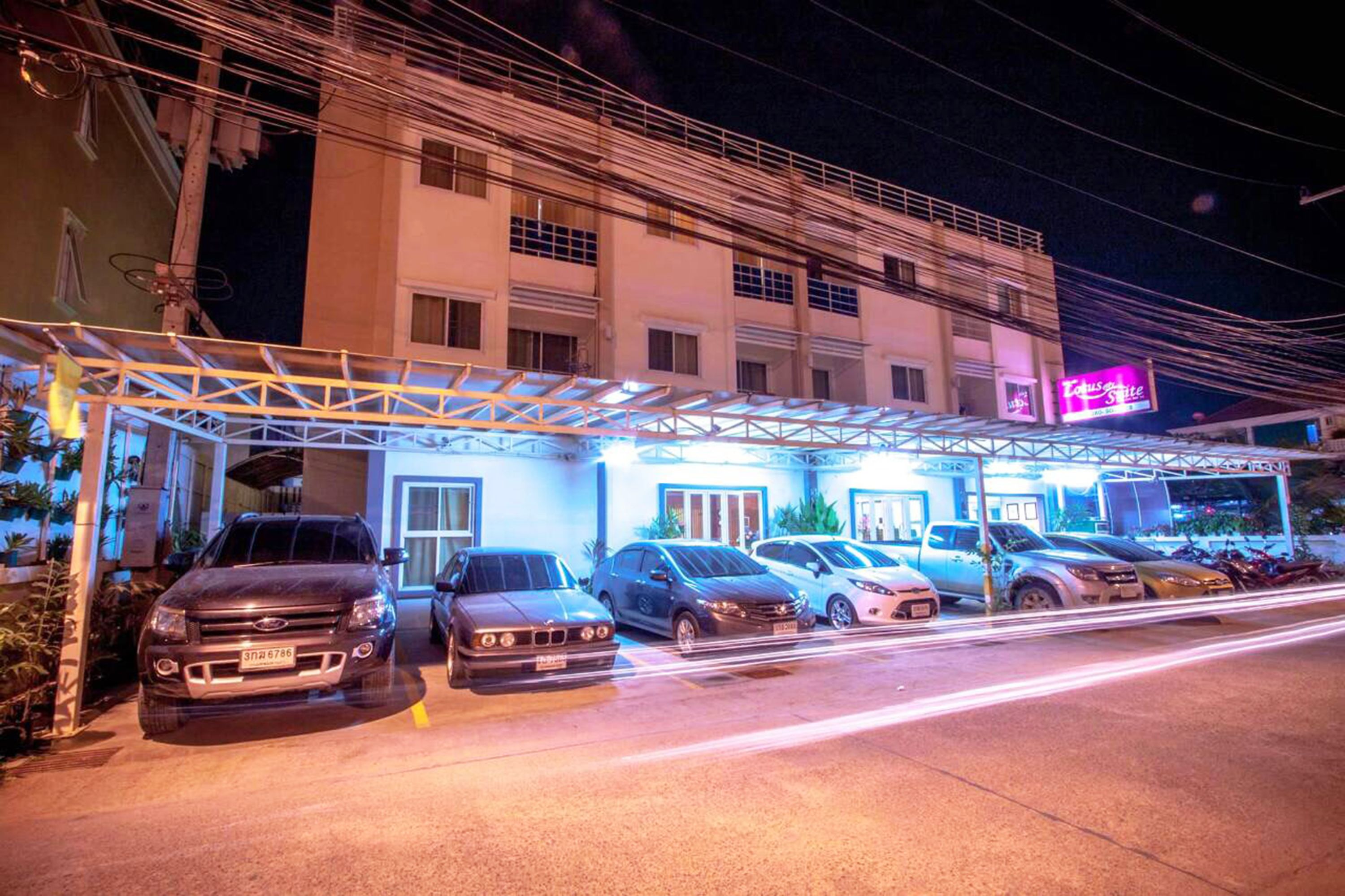 A hotel with a covered parking area and multiple cars parked in front.